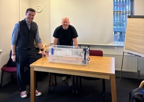 Teacher Lee Forster (left) and Nick Roberts (Wellbeing Challenge CIC) with the pupil's invention prototype